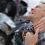 Person experiencing back and neck pain after a car accident.