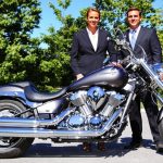 Motorcycle on road with two lawyers nearby.