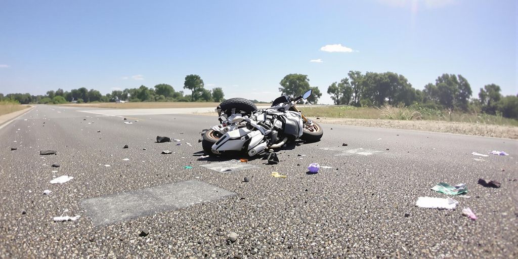 Motorcycle accident scene with road and debris.