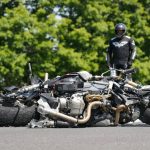 Motorcycle rider and damaged bike on road.