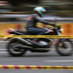 Motorcycle in motion with caution tape.