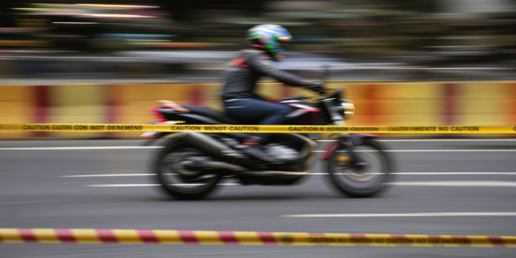 Motorcycle in motion with caution tape.