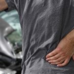 Person holding their back in pain after a car crash.