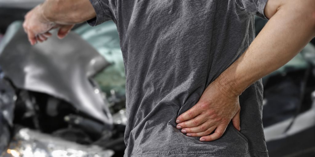 Person holding their back in pain after a car crash.