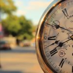 Clock with blurred city street in background.