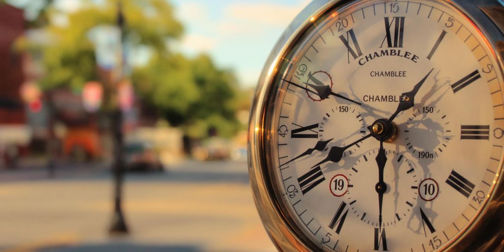 Clock with blurred city street in background.