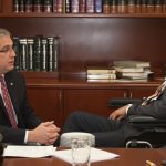 Lawyer consulting injured motorcyclist in wheelchair indoors.