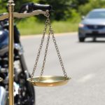 Motorcyclist on road, car behind, legal scales nearby.