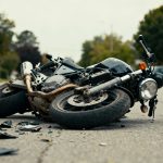 Motorcycle accident scene with damaged bike on road.