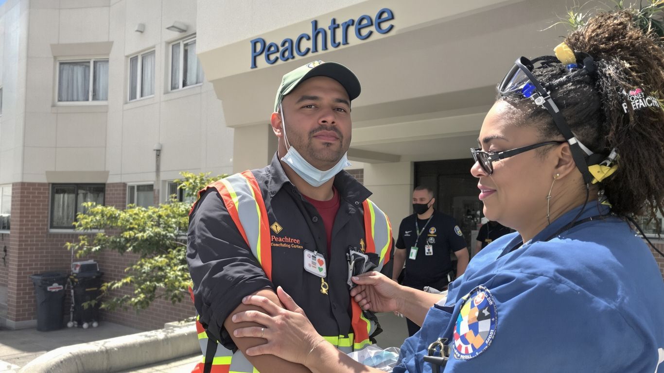 Injured worker receiving help near Peachtree building.